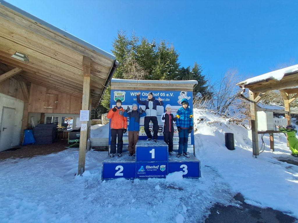 Die stolzen Skifahrer stehen auf einem Podest mit den Plätzen drei bis eins. 