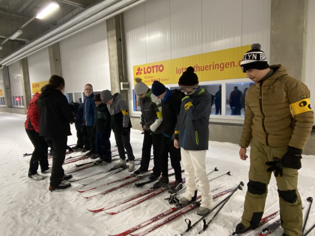 Die Schüler stehen auf Ski und machen sich mit den Sportgeräten vertraut. 