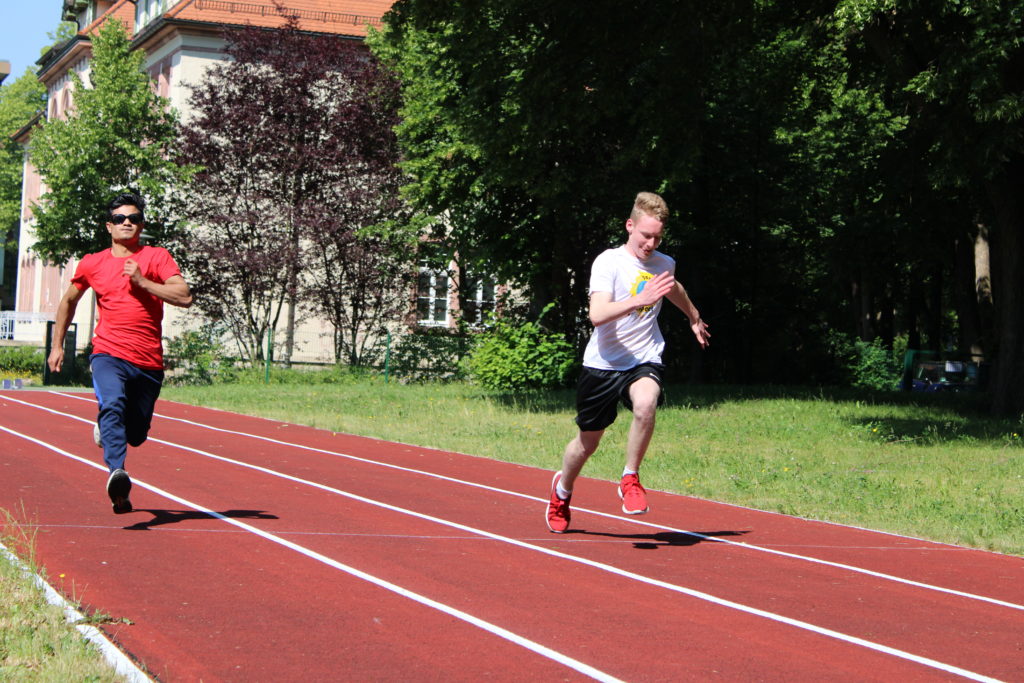Zwei Schüler treten im Sprint bei sonnigem Wetter gegeneinander an.