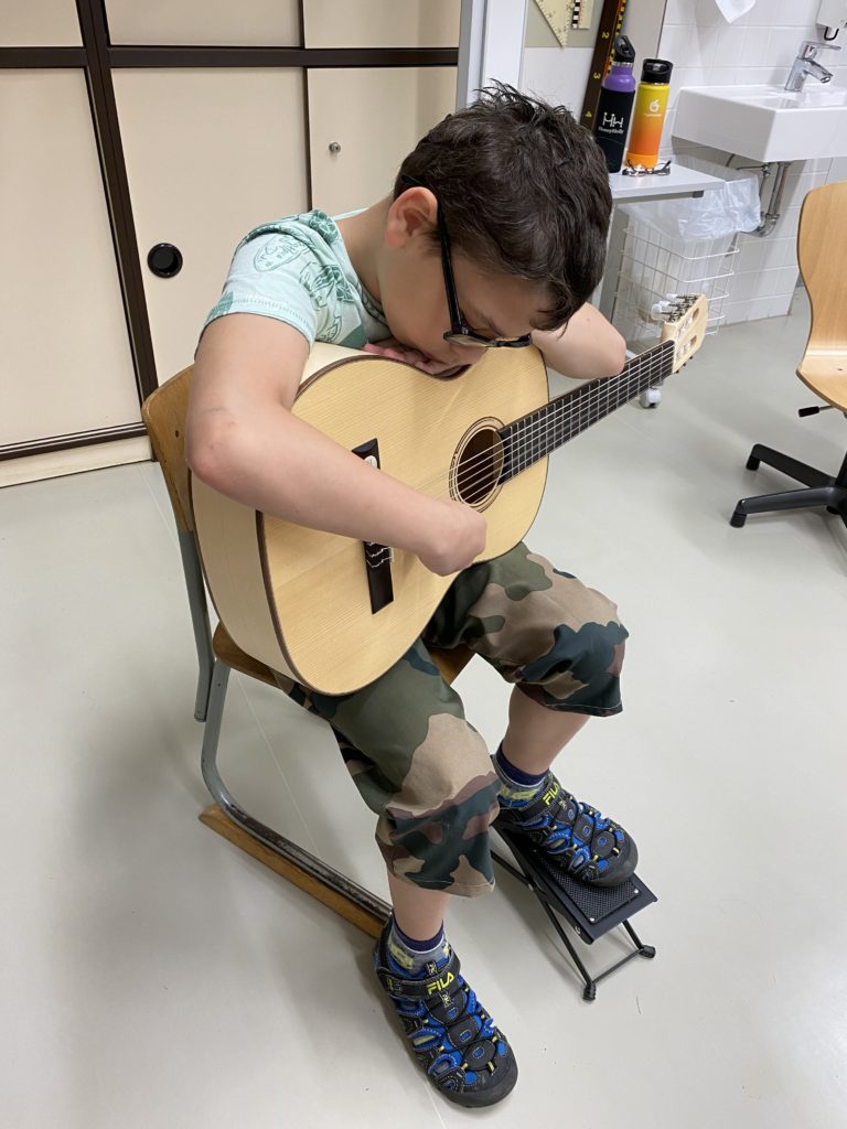 Ein Junge zupft auf einer Gitarre.