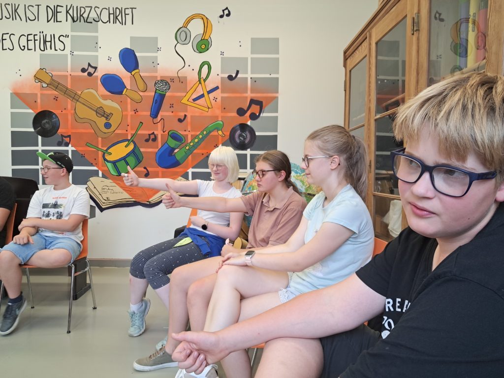 Eine Gruppe von Schülern der Klasse 7a sitzt in einem Stuhlkreis und stimmt zu einem Thema ab.