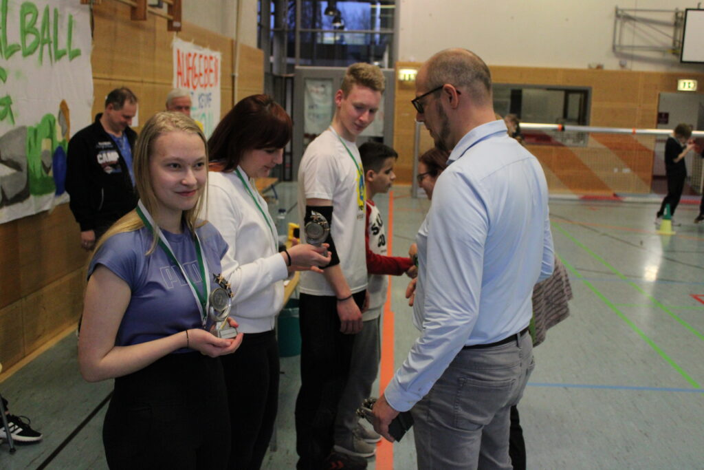 Schülerinnen und Schüler des Siegerteams erhalten einen Pokal und eine Medaille