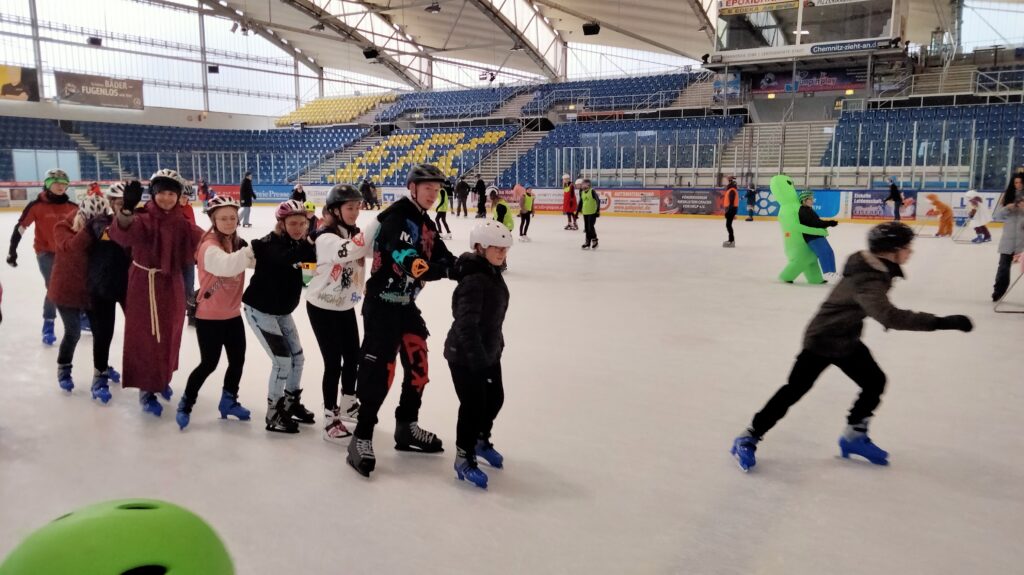Teilnehmer des Eisfaschings bilden eine lange Eislaufkette