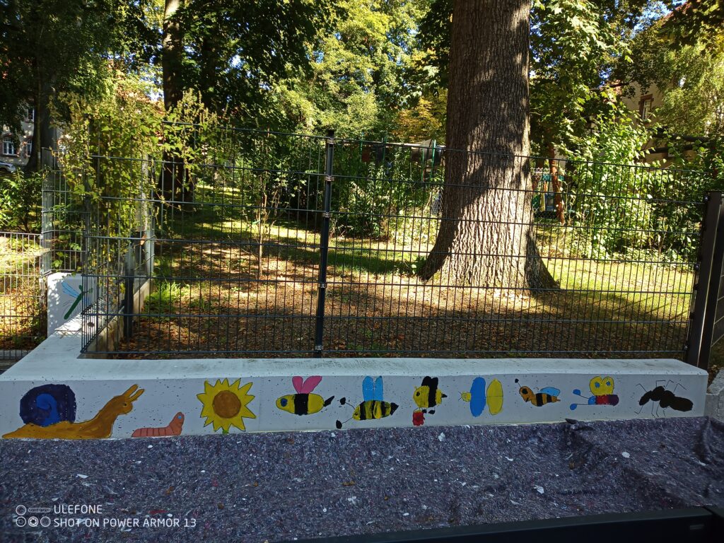 eine Wand auf der Bilder von Biennen, Schenken, Würmer und Schmetterlinge drauf sind