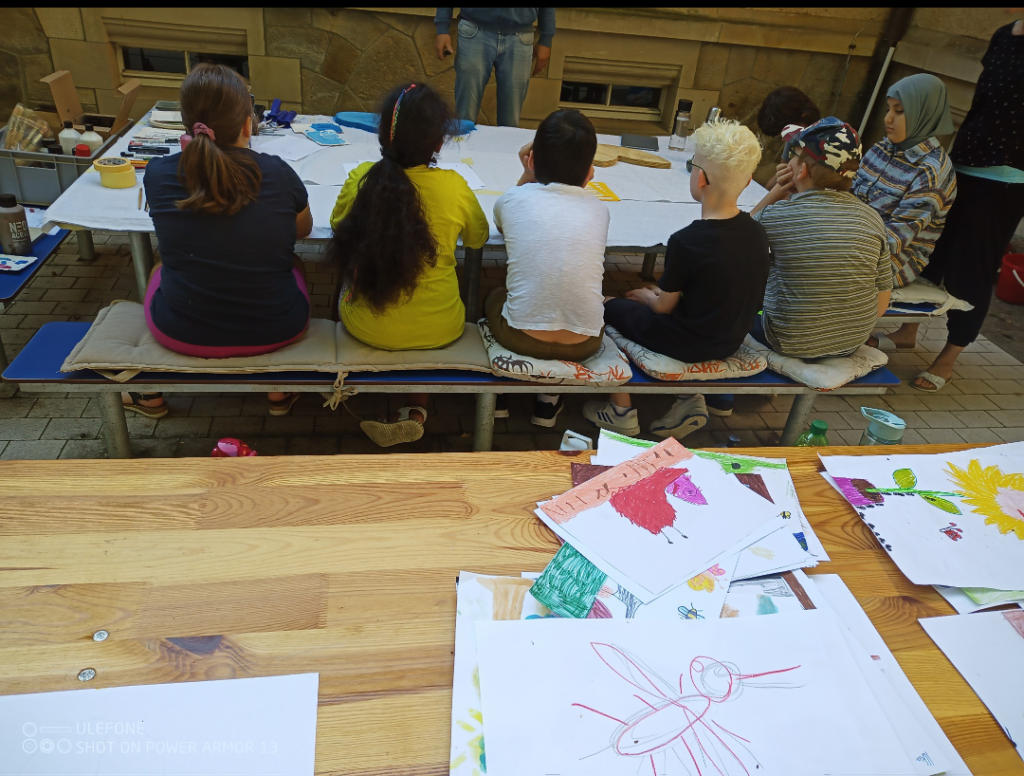 Kinder sitzen am Tisch und mahlen Bilder 