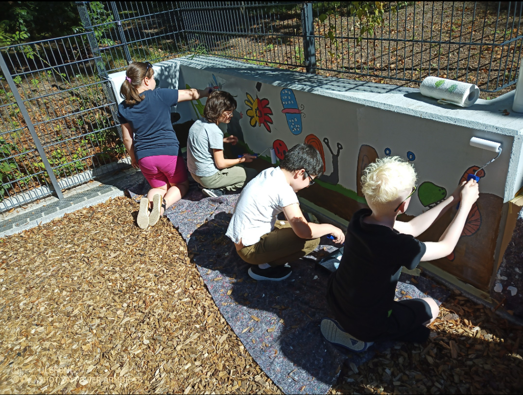 Eine Gruppe Kinder malt Bilde an die Want 