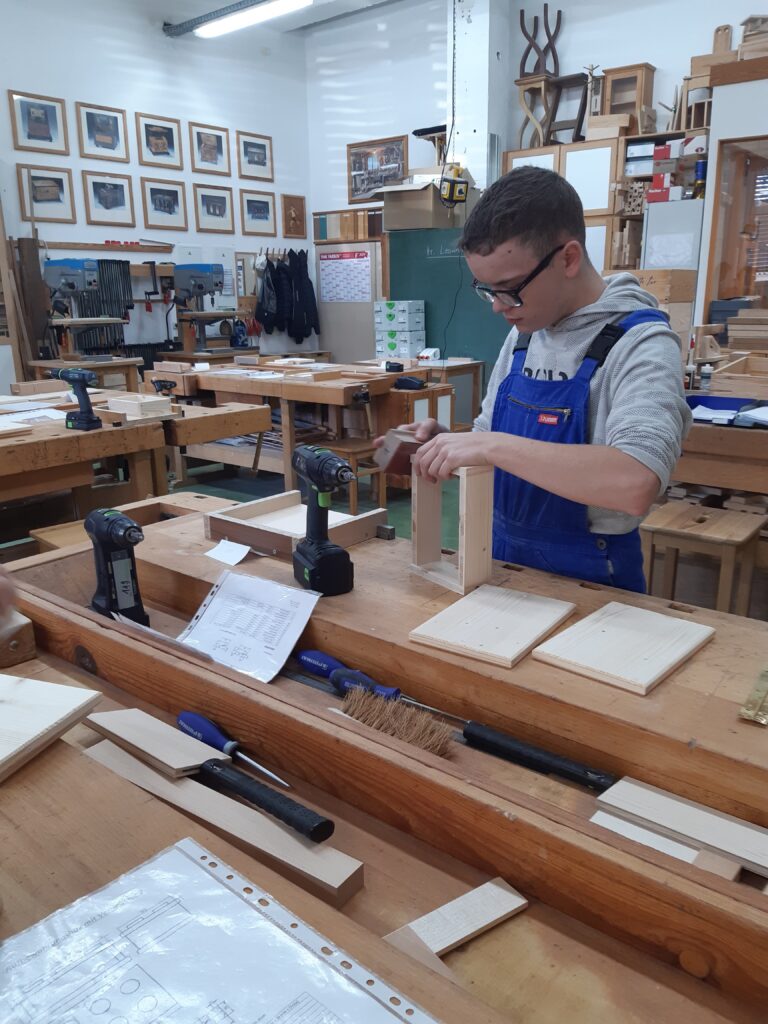 Ein Schüler bearbeitet Holz mit einem Schleifklotz