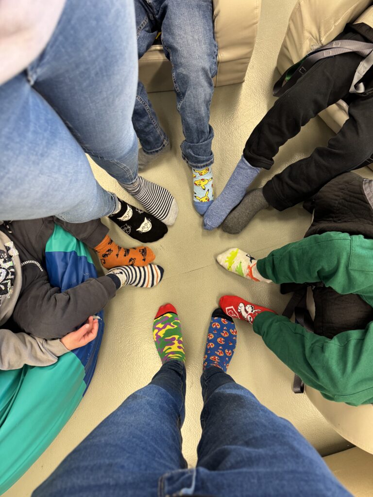 Blick von oben auf insgesamt 12 Füße, alle Socken sind verschieden.
