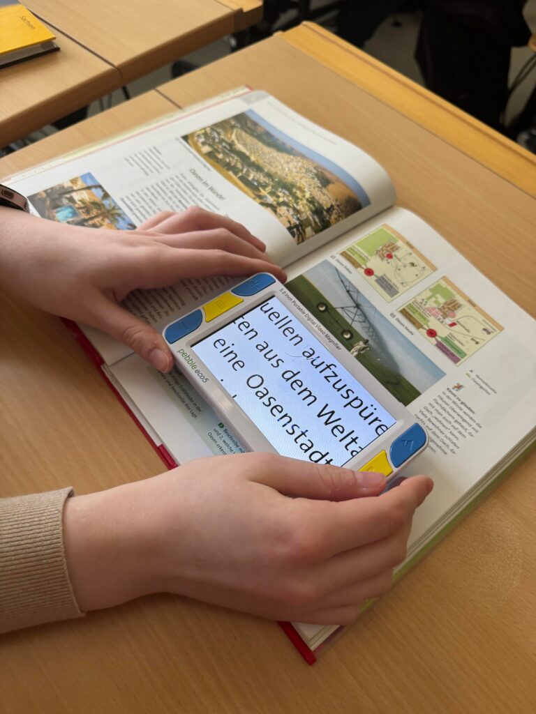 Man sieht eine Person die ein Gerät zur Vergrößerung für Texte zeigt