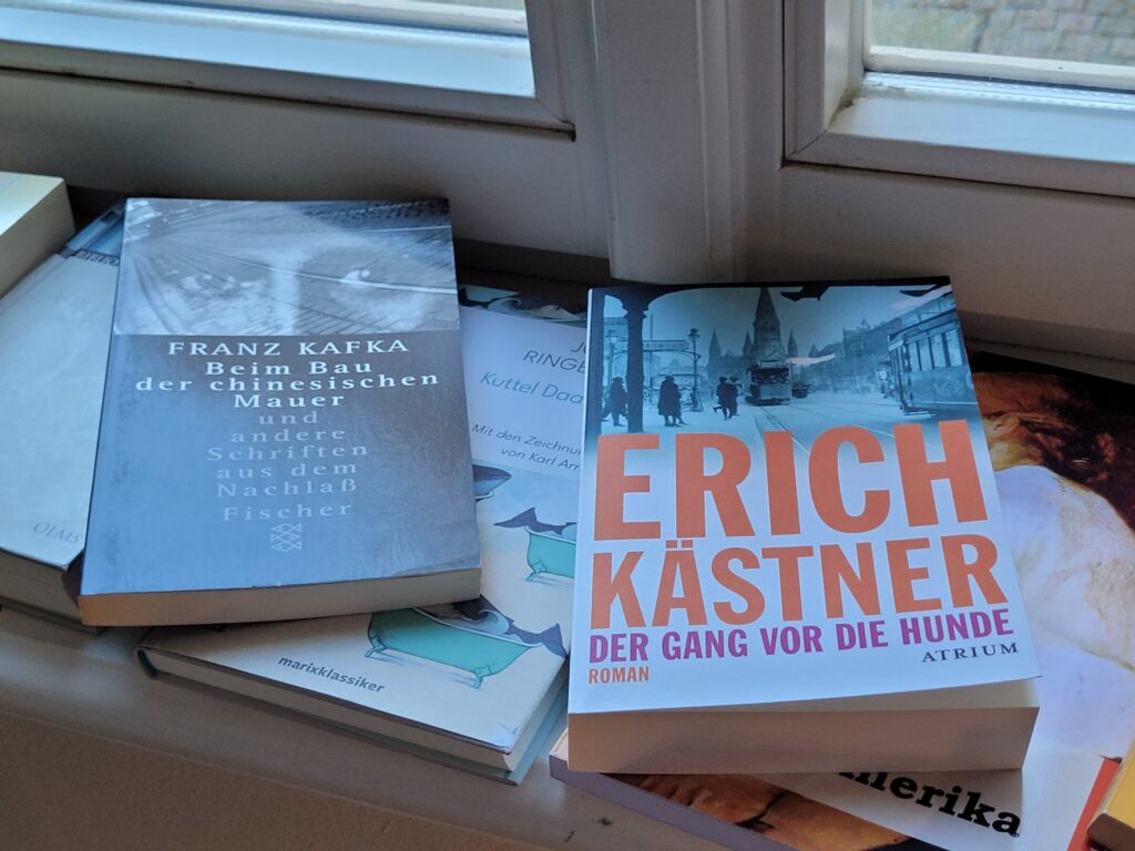 mehrere Bücher liegen auf einem Fenstersims, ganz oben Bücher von Franz Kafka und Erich Kästner