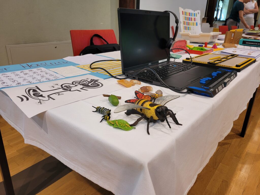 Es sind ein Laptop mit Braille-zeile und Insekten wie zum Bieispiel eine Biene zu sehen