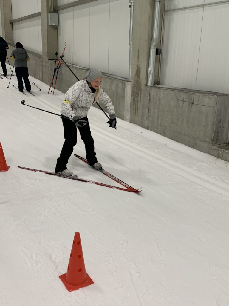 hier ist eine Schülerin auf Ski zu sehen wie sie einen kleinen Berg runterfährt