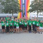 Gruppenfoto aller Läuferinnen und Läufer. Alle tragen grüne Shirts, einige haben die Arme noch oben geworfen.