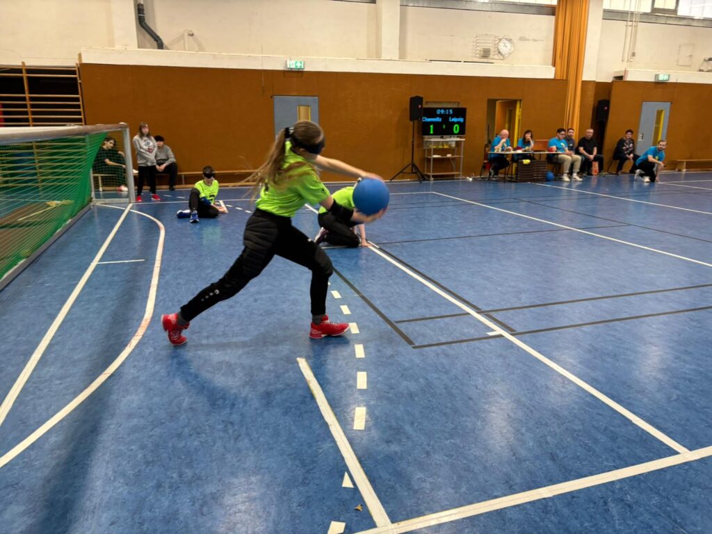 eine Schülerin beim Schuss in einem Spiel im Goalball. ihre Mitspieler sind auf ihrer Position
