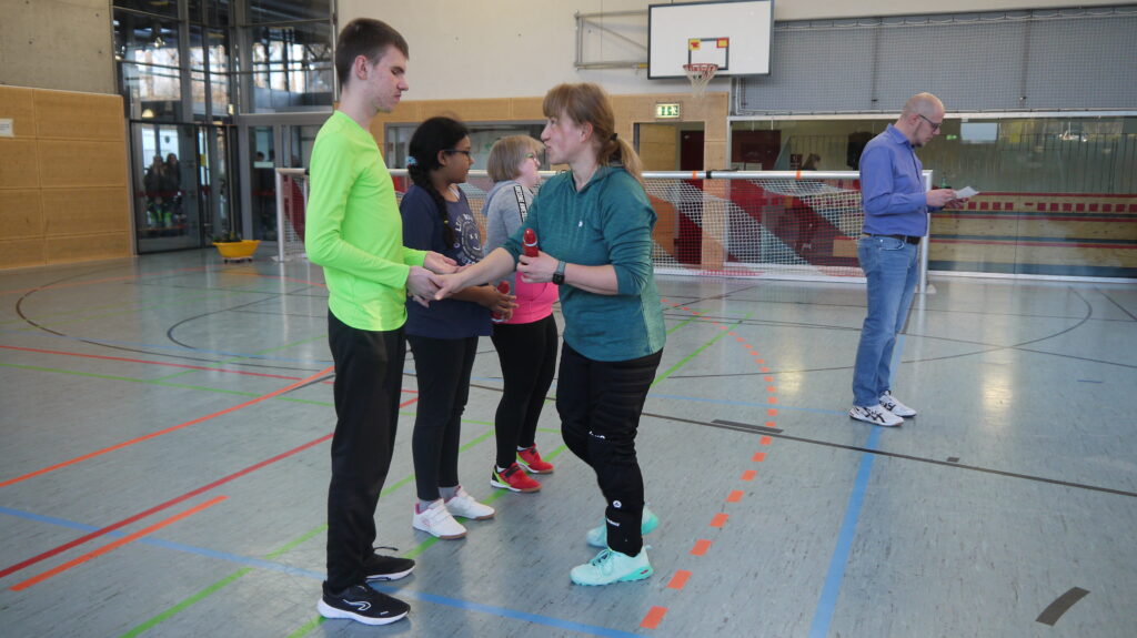 Hier bekommen drei schüler ein Schokoweihnachtsmann zu Siegerehrung zum 3. Platz von der Sportlehrerin