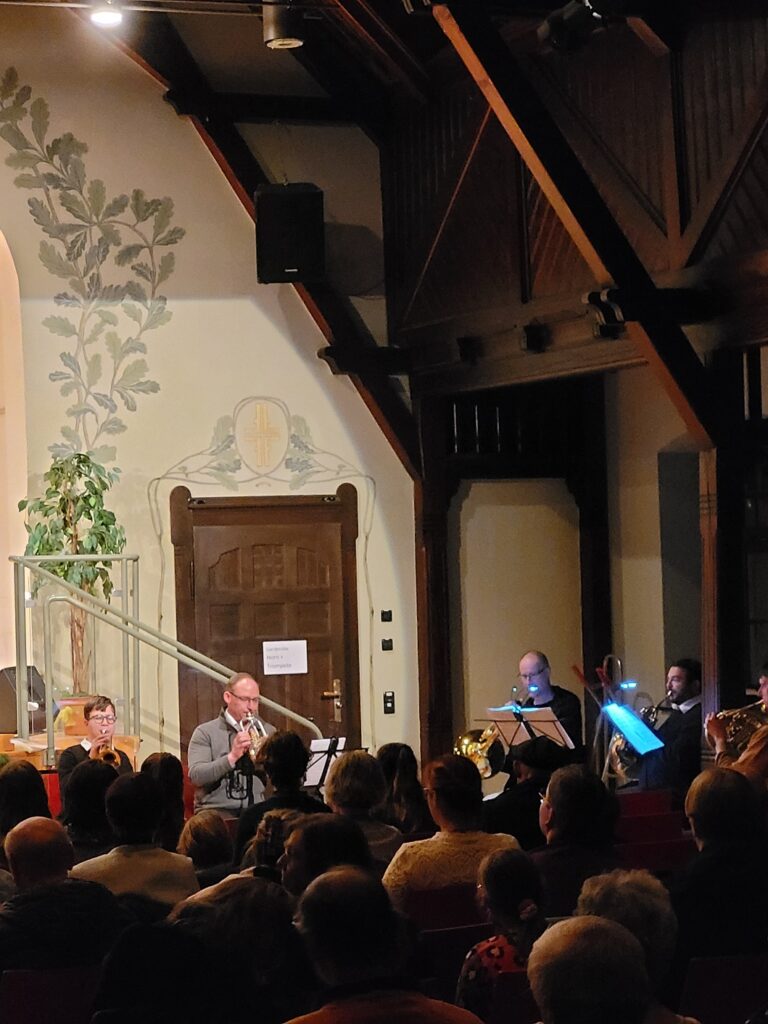Mehrere Musiker spielen Blasinstrumente vor ihnen sitzen die Publikumen.