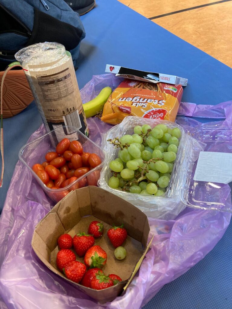 Snacks für die Spielpause in der Turnhalle: Erdbeeren, Weintrauben, Tomaten, Reiswaffel, Salzstangen und eine Banane