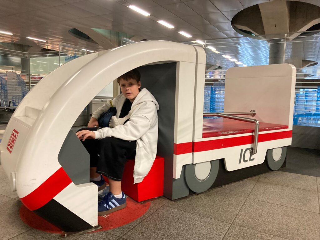 Der jüngste Schüler sitzt am Hauptbahnhof Berlin in einem Spielzug.