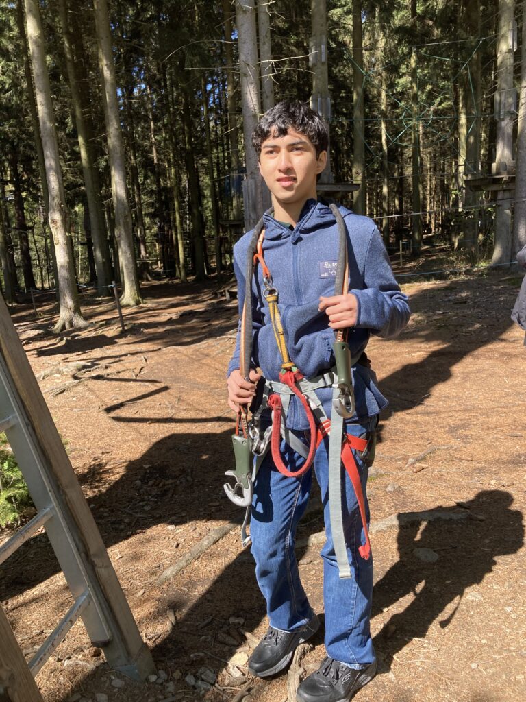 ein Junge steht mit Kletterausrüstung auf dem Wald Boden
