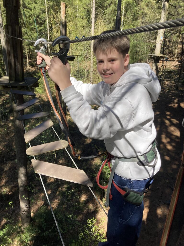 ein Junge befestigt ein Karabiner am Seil fest